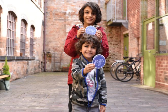 Two children stand in the courtyard holding small "The City Beautiful" blue plaques.