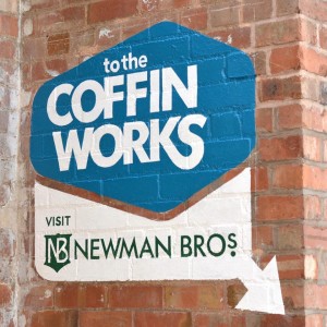 The Coffin Works sign painted on a brick wall.
