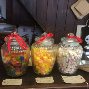 various Sweets in three glass jars standing on a wooden surface