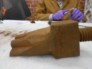 Rusty object next to a piece of paper on a white surface