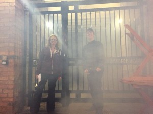 Luke and a member of cw staff stand in front of cw gates, the air around them is hazy with a fine mist