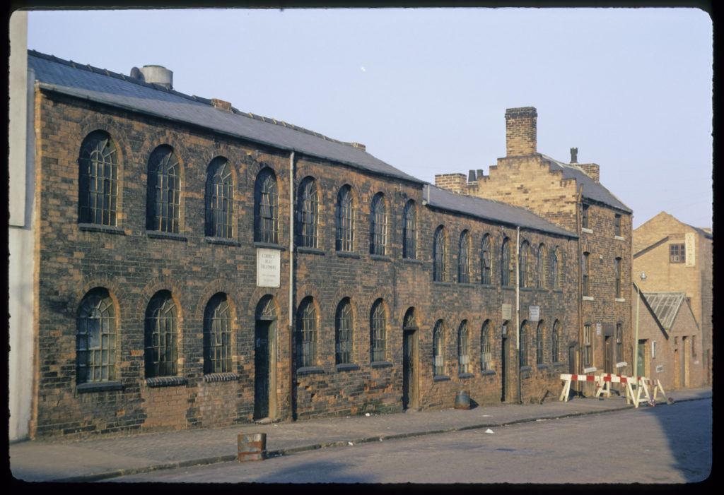 late 60s photo showing brick factory, in front is an street empty