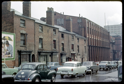 60s photo of brick factories, cars pass in the street in front