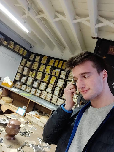 David in the Warehouse holding a coffin handle to his ear as if a telephone receiver