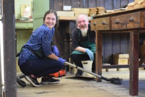 francis and volunteer crouch with vacuum on the stock room floor