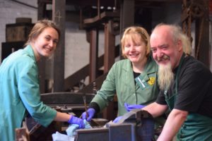 three volunteers wearing purple gloves in the stamp room