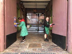 two volunteers clean courtyard doors