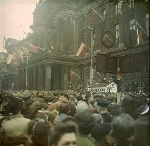 A crowd stands in front of the Council House for VE Day Celebrations, May 1945. There are world flags on display.