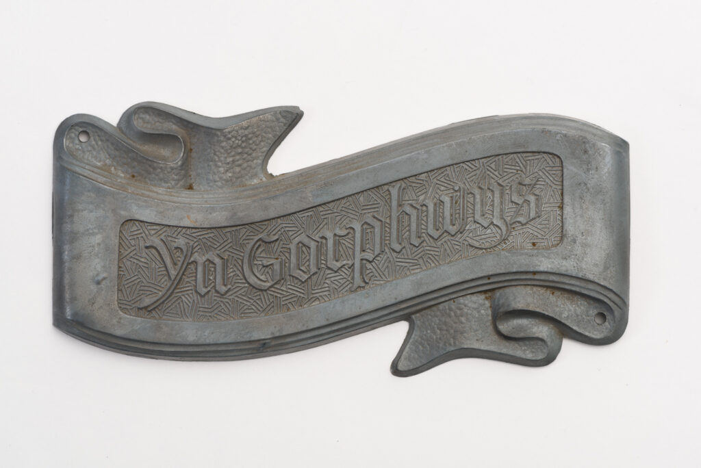 Zinc ribbon shapes coffin ornament. Text says "At rest" in welsh