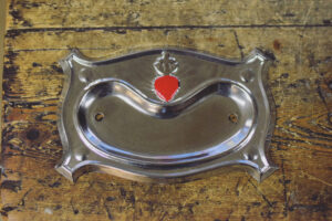 Silver coloured backplate featuring small sacred red heart at top centre