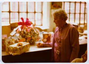 60s grainy photo of Dolly Dunsby with gifts behind her in the Shroud Room