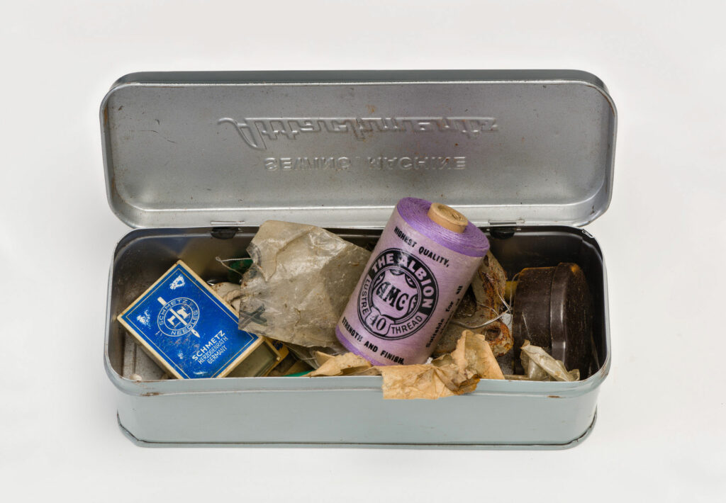 Open Sewing tin featuring purple sewing thread and other items