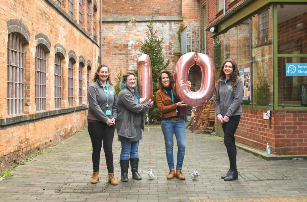 Group of women holding balloons that depict number 10.