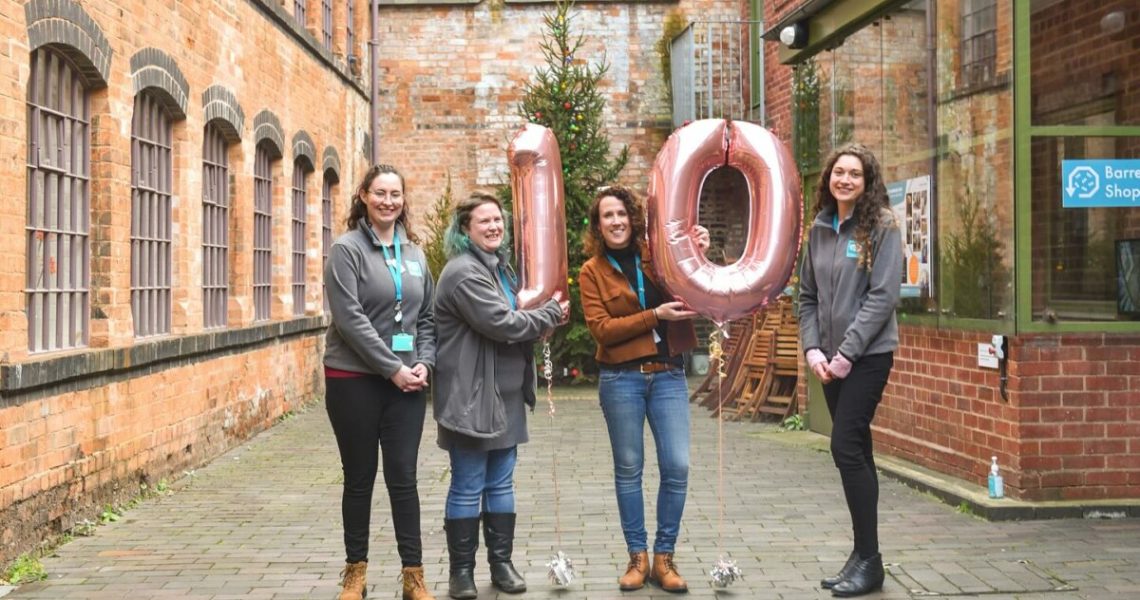 Group of women holding balloons that depict number 10.