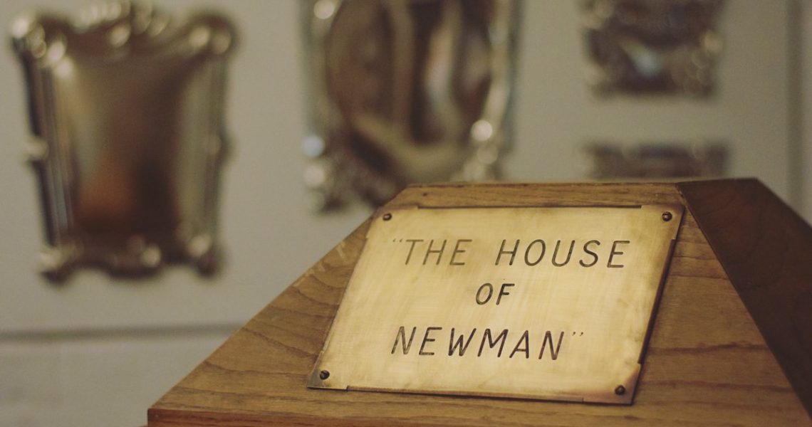 Wooden stand in foreground with Brass sign 'The House of Newman'